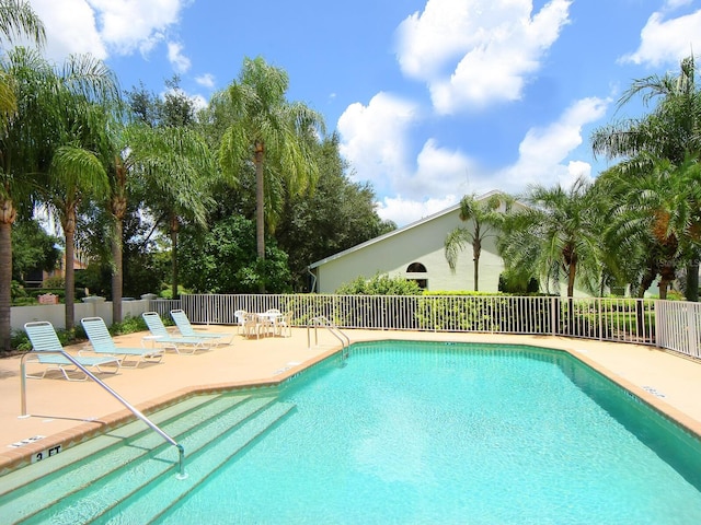 pool with a patio area and fence