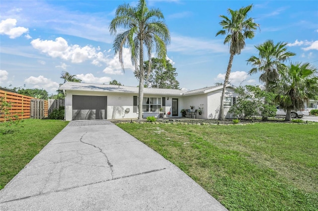 view of front of house with an attached garage, fence, concrete driveway, stucco siding, and a front lawn