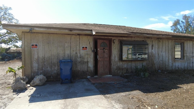 property entrance featuring roof with shingles