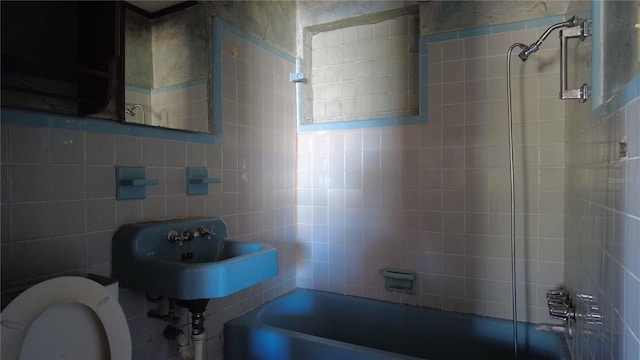 bathroom featuring toilet, tile walls, and a sink