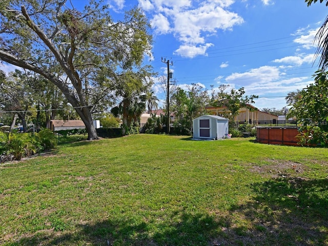 view of yard featuring a storage shed, fence, and an outdoor structure