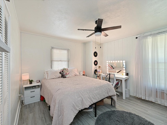 bedroom featuring a ceiling fan, wood tiled floor, and a textured ceiling