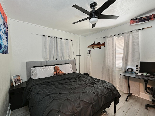 bedroom with ceiling fan, a textured ceiling, and wood finished floors