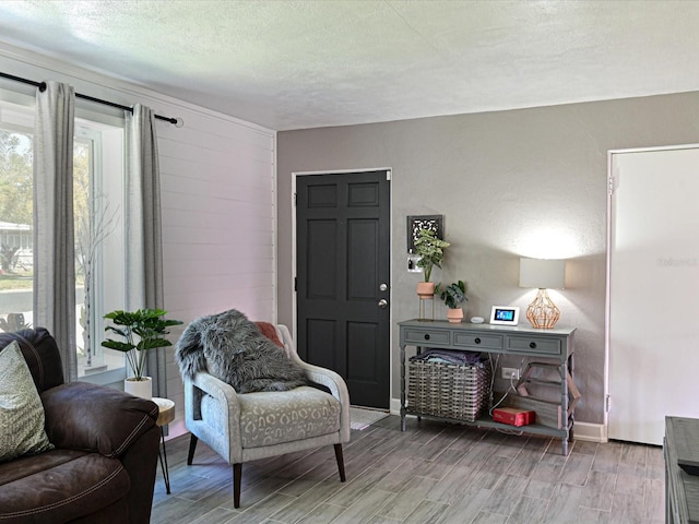 sitting room with a textured ceiling, light wood-type flooring, and baseboards