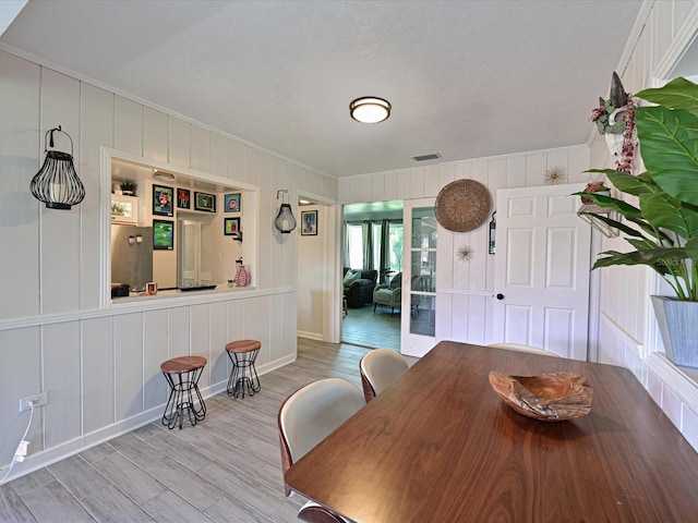 unfurnished dining area featuring visible vents, a decorative wall, and wood finished floors