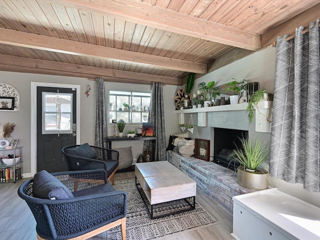 living area featuring wooden ceiling, a brick fireplace, beam ceiling, and wood finished floors