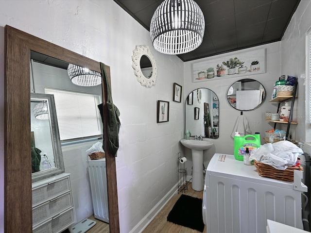 bathroom with a sink, washer / clothes dryer, wood finished floors, and a notable chandelier