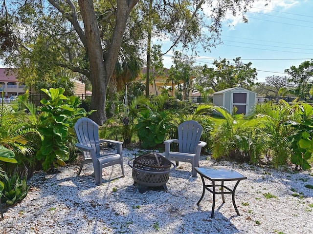 view of patio featuring a fire pit, a shed, an outdoor structure, and fence