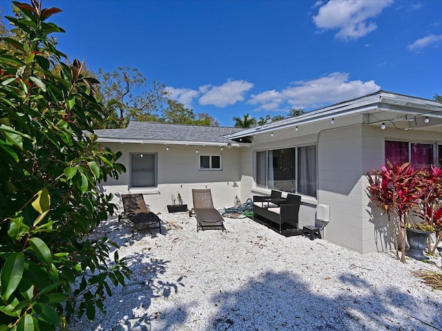 back of house featuring a patio area and roof with shingles