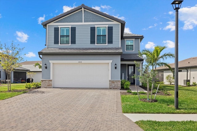 view of front of home featuring a garage, a front yard, decorative driveway, and stone siding