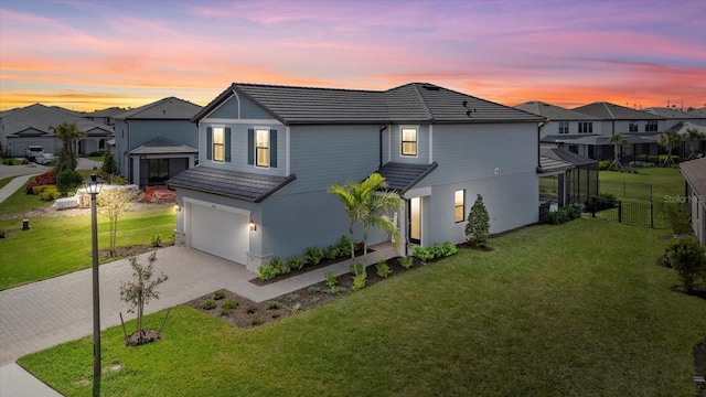 view of front of house featuring fence, a yard, a tiled roof, decorative driveway, and a residential view