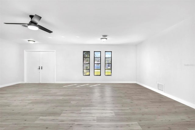 unfurnished room with baseboards, visible vents, ceiling fan, and wood finished floors