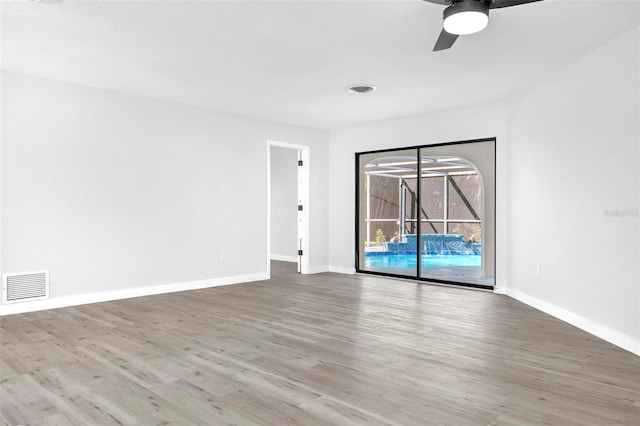 unfurnished room featuring baseboards, visible vents, and wood finished floors