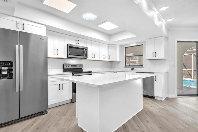 kitchen with a center island, crown molding, light wood finished floors, stainless steel appliances, and white cabinetry