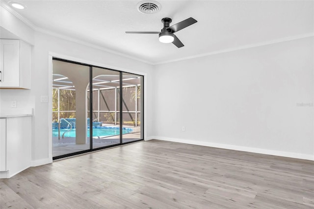 empty room featuring baseboards, light wood finished floors, visible vents, and crown molding