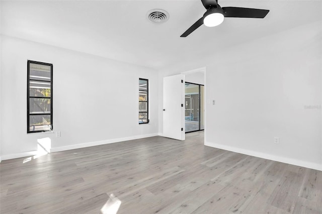 unfurnished room with ceiling fan, wood finished floors, visible vents, and baseboards