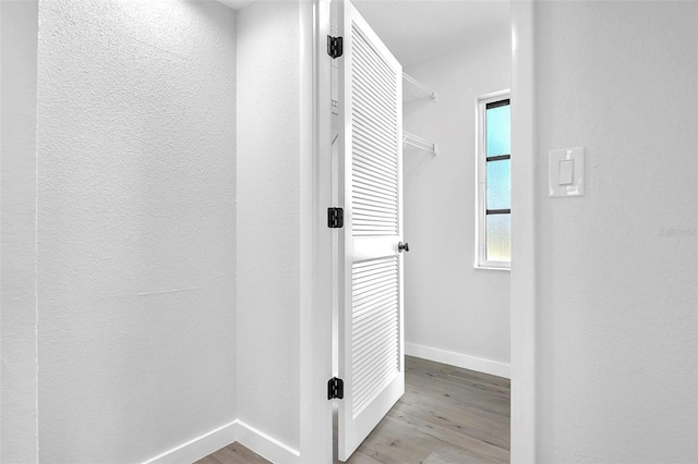 corridor featuring baseboards and wood finished floors