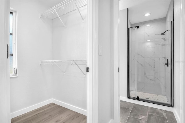 full bath featuring a walk in closet, baseboards, and a marble finish shower