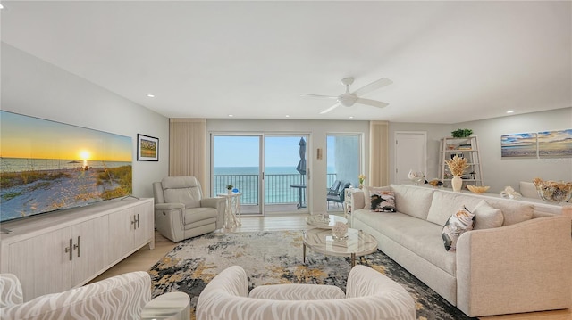 living room with a water view, light wood-style flooring, ceiling fan, and recessed lighting