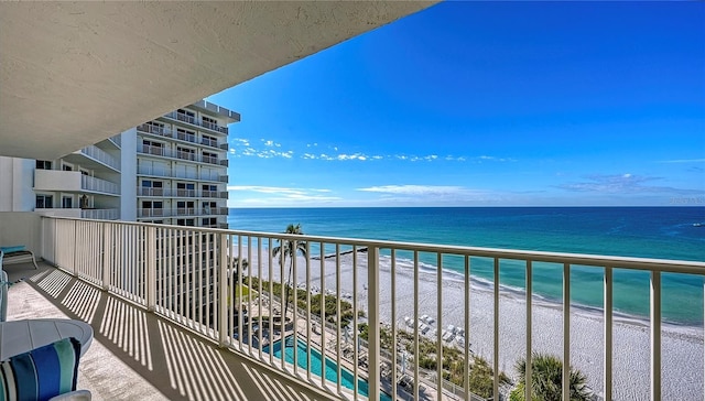 balcony with a water view and a view of the beach