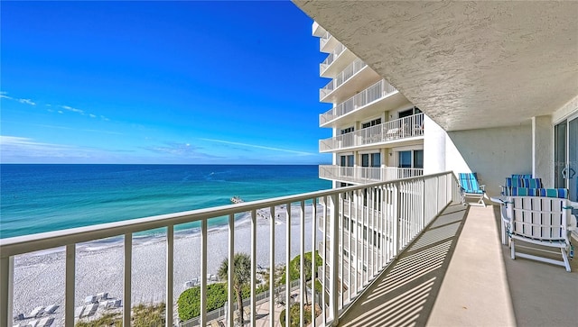 balcony with a water view and a view of the beach