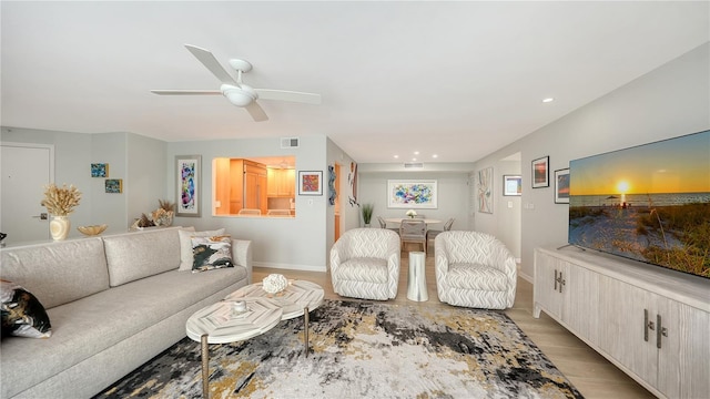 living room with recessed lighting, visible vents, a ceiling fan, light wood-type flooring, and baseboards