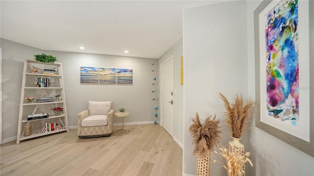 living area with baseboards, wood finished floors, and recessed lighting