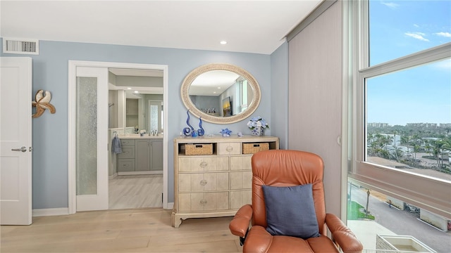 living area featuring baseboards, visible vents, and light wood finished floors