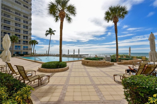 view of pool with a water view and a patio