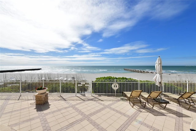 view of patio / terrace featuring a water view and a beach view