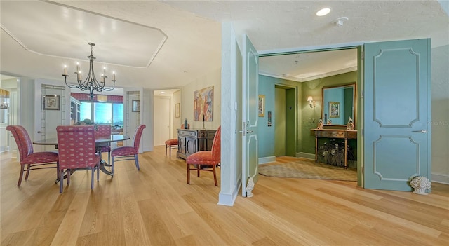 dining space with baseboards, a notable chandelier, ornamental molding, and light wood finished floors