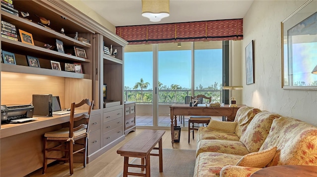 home office featuring a textured wall, light wood finished floors, and built in study area