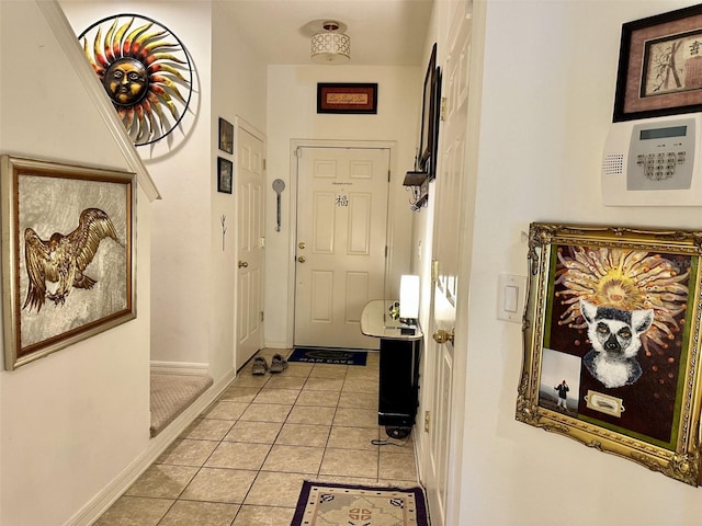 doorway to outside featuring baseboards and light tile patterned flooring