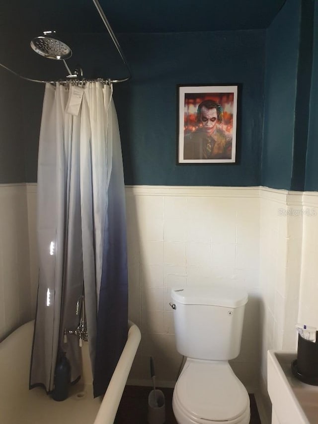 775 36th Ave S, Saint Petersburg, FL 33705 - bathroom with toilet, wainscoting, tile walls, and a shower with shower curtain