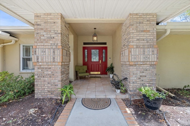 view of exterior entry with brick siding and stucco siding