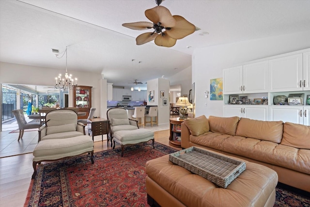 living area with lofted ceiling, light wood-style floors, visible vents, and ceiling fan with notable chandelier