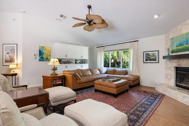 living area with visible vents, a ceiling fan, lofted ceiling, wood finished floors, and a fireplace