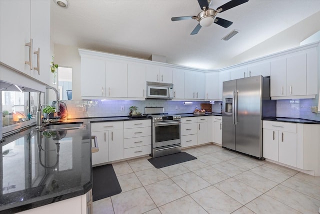 kitchen featuring visible vents, decorative backsplash, appliances with stainless steel finishes, white cabinets, and a sink