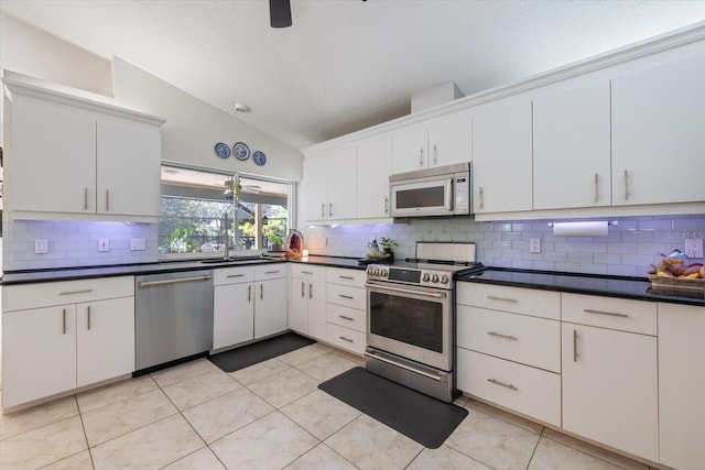 kitchen featuring dark countertops, vaulted ceiling, stainless steel appliances, and decorative backsplash