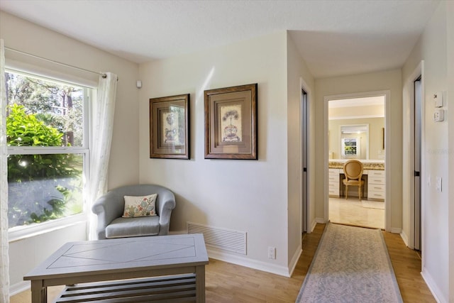 sitting room featuring light wood-style flooring, visible vents, and baseboards