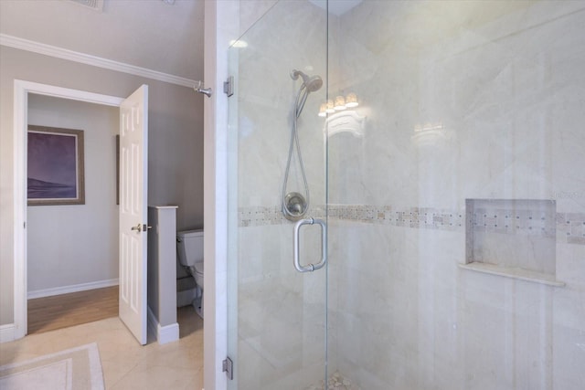 bathroom featuring tile patterned flooring, toilet, baseboards, ornamental molding, and a stall shower