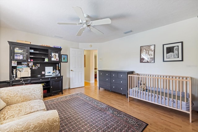 bedroom featuring wood finished floors, visible vents, and a ceiling fan