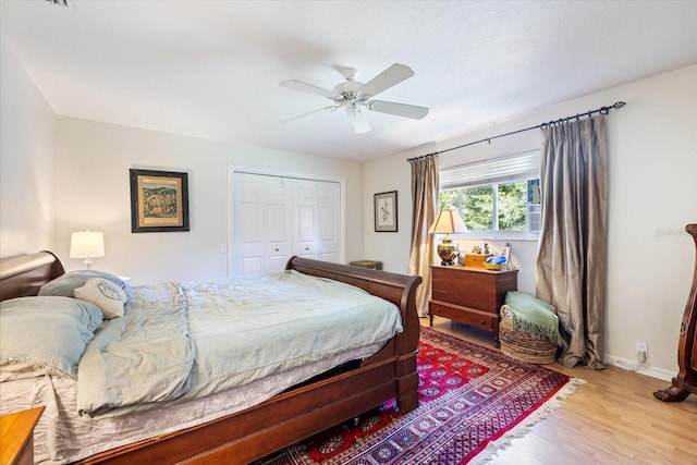 bedroom with a closet, wood finished floors, a ceiling fan, and baseboards