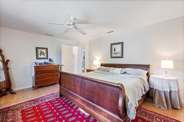 bedroom featuring ceiling fan, wood finished floors, visible vents, and baseboards