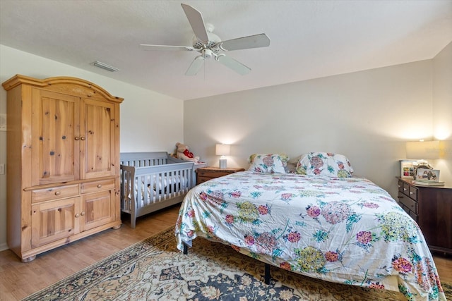 bedroom featuring light wood-type flooring, visible vents, and a ceiling fan