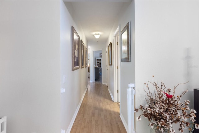 hallway featuring light wood-type flooring and baseboards