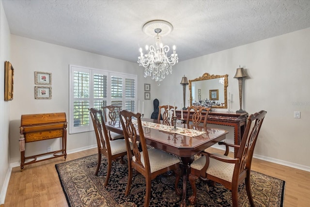 dining space featuring light wood-type flooring, baseboards, a chandelier, and a textured ceiling