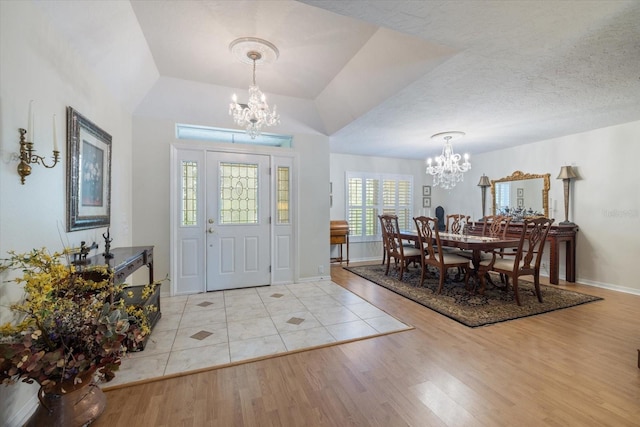 entryway featuring a textured ceiling, light wood-style floors, baseboards, and an inviting chandelier