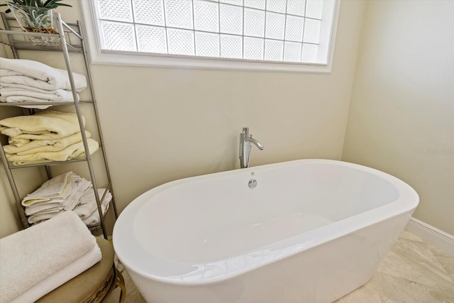 bathroom featuring a soaking tub and baseboards