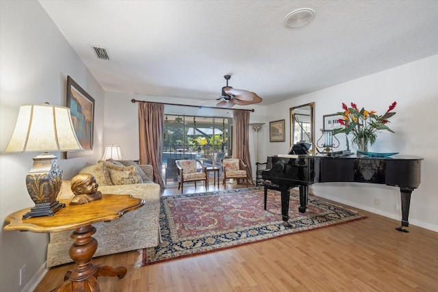 living area featuring baseboards, wood finished floors, visible vents, and a healthy amount of sunlight